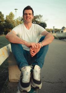 Serge De Marre, Voice Arts® Award nominee, sitting casually on a park bench in Budapest, reflecting on his journey as an international voice actor. The photo captures his connection to the city where he lived for two years before moving to Houston, TX.