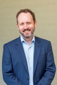 A head and shoulders shot of Martin Kennedy Home in place wearing a shirt and suit jacket