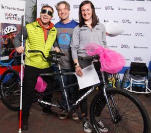 Three people pose with a tandem bike